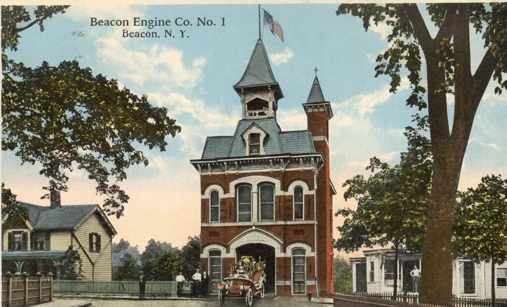 A vintage hand-colored postcard of Beacon Engine Co. No. 1 in Beacon, NY. The red brick firehouse stands prominently with its tall, grey-roofed bell tower and a smaller matching side tower. A red motorized fire engine is exiting the main bay, and the surrounding neighborhood shows lush green trees and Victorian-era houses.