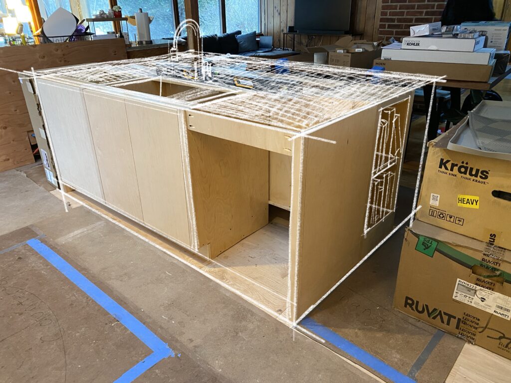A close-up of a custom kitchen island under construction at MCM Reno. A digital white-line overlay illustrates the planned countertop, sink, and faucet placement over the light-wood cabinet frame, highlighting the precise design process of this mid-century modern renovation.