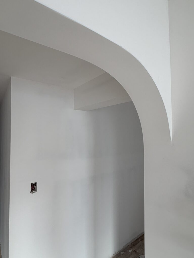 A detailed close-up of a custom arched doorway at Hudson House. The smooth, sculptural curve of the drywall reflects the refined modern craftsmanship of this townhouse renovation, creating a soft architectural transition between spaces.