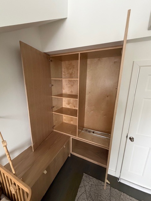 A detail shot of the custom cabinetry at Shokan Reno, showing the open doors of a tall birch plywood wardrobe. The interior reveals adjustable shelving and high-quality craftsmanship, part of a cohesive built-in storage solution that maximizes space in the home.