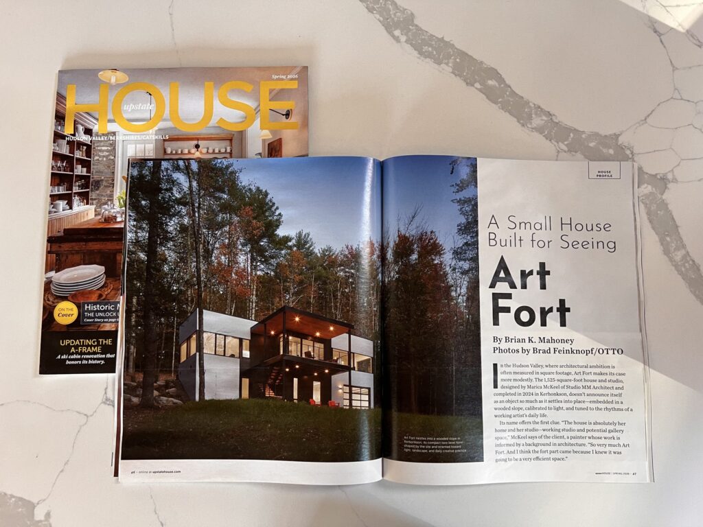Upstate House magazine Spring 2026 issue featuring Studio MM’s "Art Fort" project. The image shows a sleek, modern home with large windows nestled in a wooded Hudson Valley landscape.