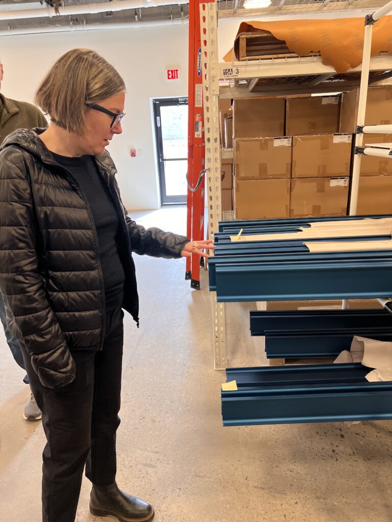Betsy, a team member at Studio MM Architect, touches a textured, matte-blue finish sample while touring the RBW Lighting factory in Kingston, NY.
