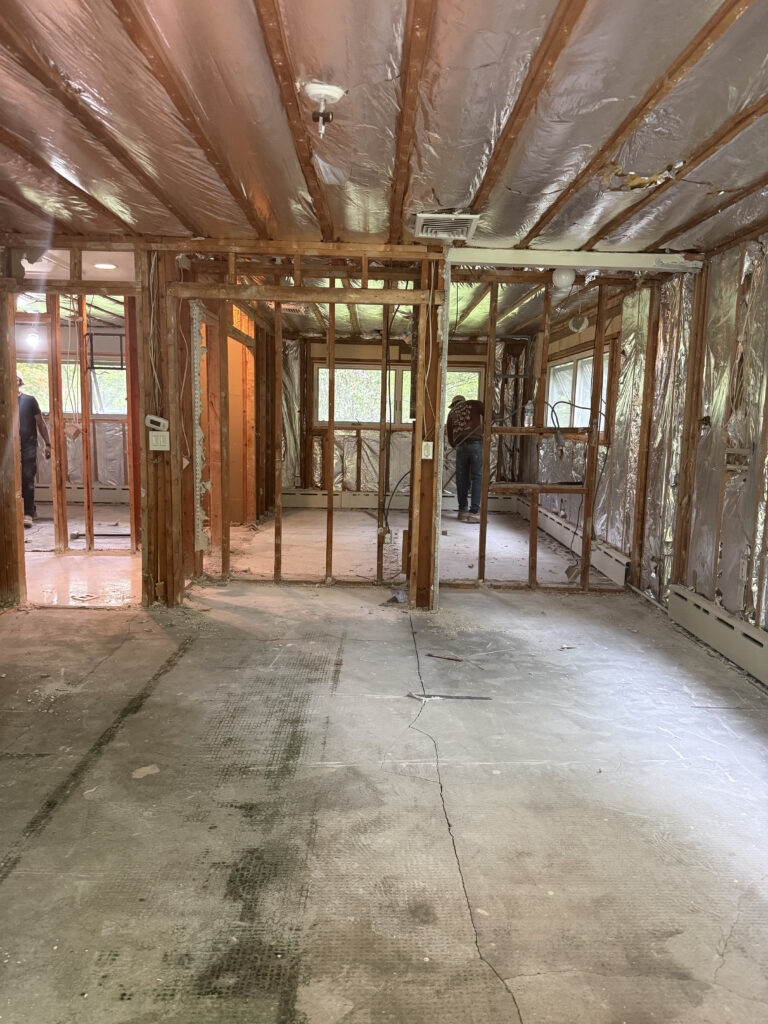 Wide demolition view at MCM32 showing existing concrete slab removed and structural framing exposed, preparing the space for renovation.