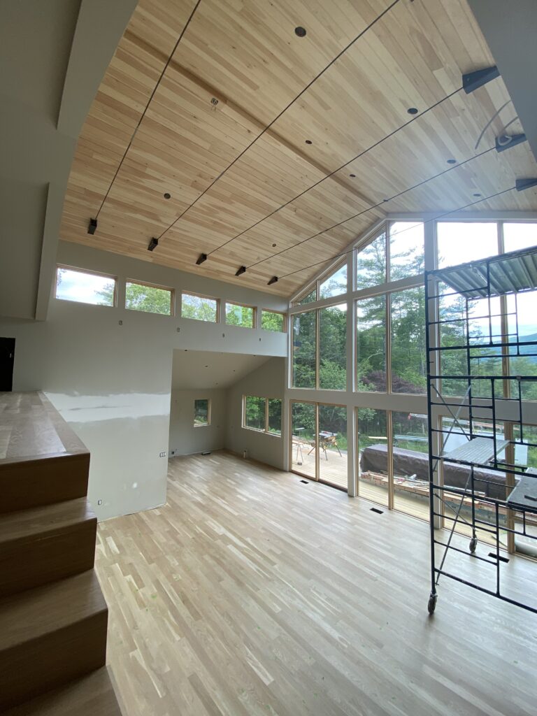 Interior view of Pond Lane showing painted walls and installed wood floors, with natural light highlighting the progress of the renovation.