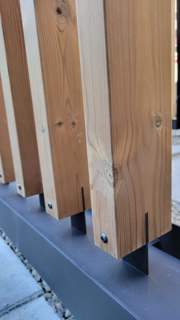Cedar battens seated in black steel base plate brackets with visible saw-tooth joinery