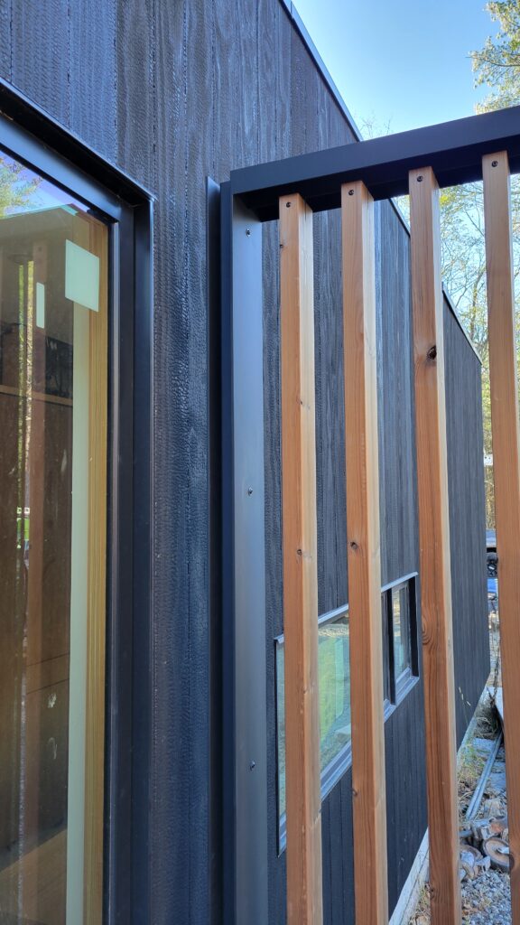 Corner detail of charred wood siding meeting a cedar batten screen wall at Fermata