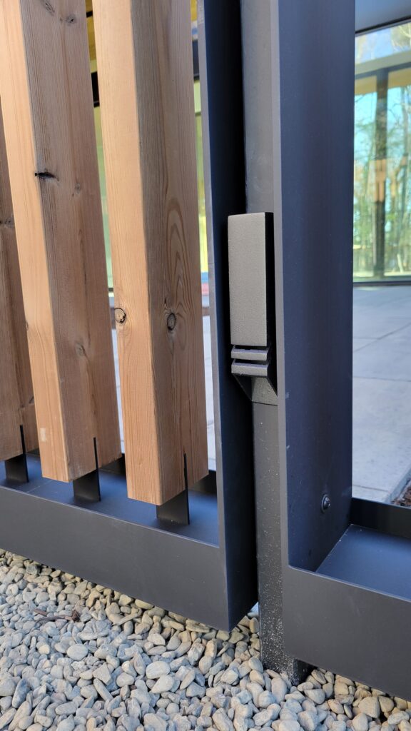 Close-up of a black steel post and hardware pull integrated into the batten screen wall