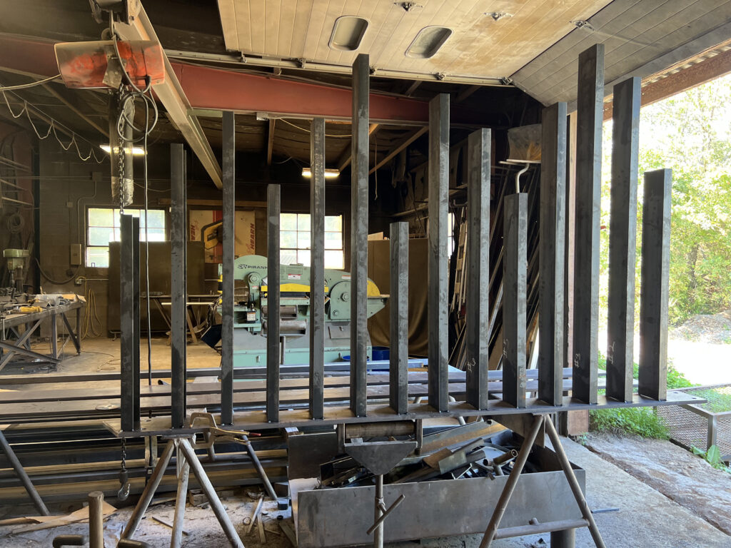 Custom steel fence posts being fabricated and numbered in a metal shop before installation
